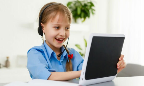 Smart little schoolgirl with digital tablet in a classroom. Child in an elementary school. Education and learning for kids.
