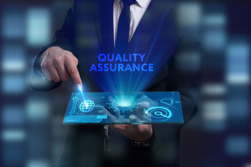 Futuristic hologram display saying "quality assurance" with a man in a suit pointing to it