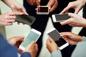 Cropped shot of a group of unidentifiable businesspeople using their smartphones in a huddle.