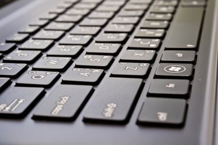 Close-up of a black computer keyboard showing English and Arabic characters on the keys.