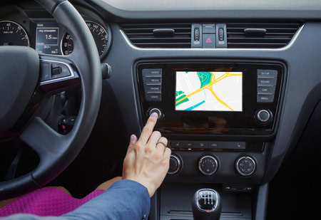Person touching a button on a car's navigation system.